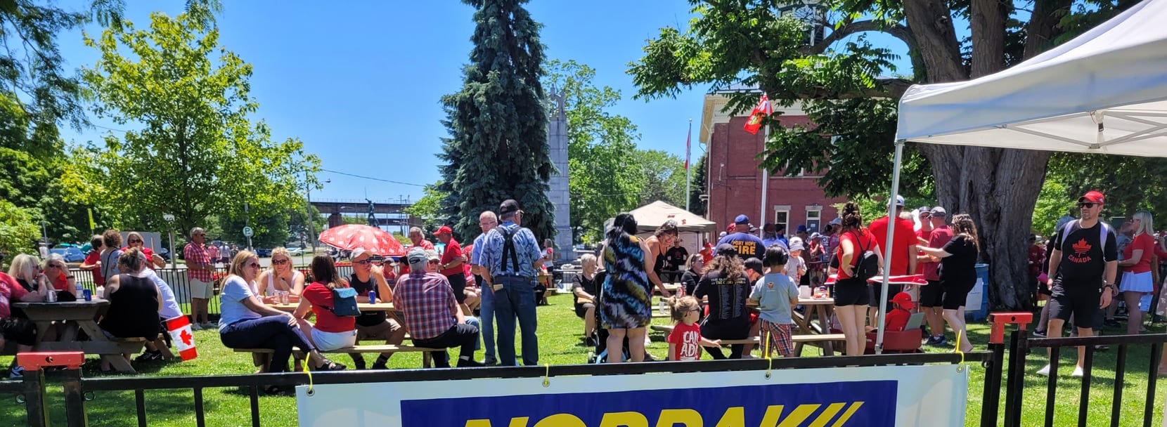 Community celebration in a park with a Norpak banner in the foreground